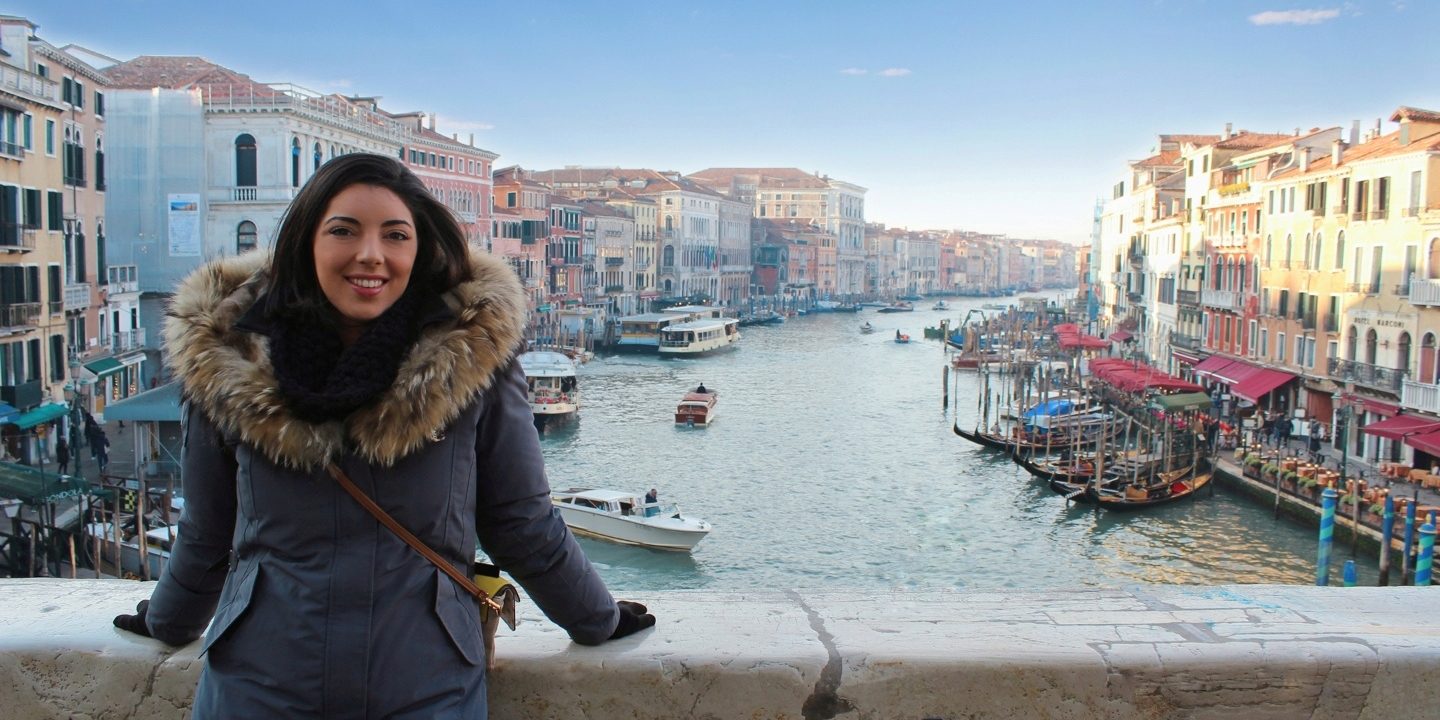 une fille est assise sur la rambarde du Pont Rialto avec en arrière plan la vue du Grand Canal de Venise