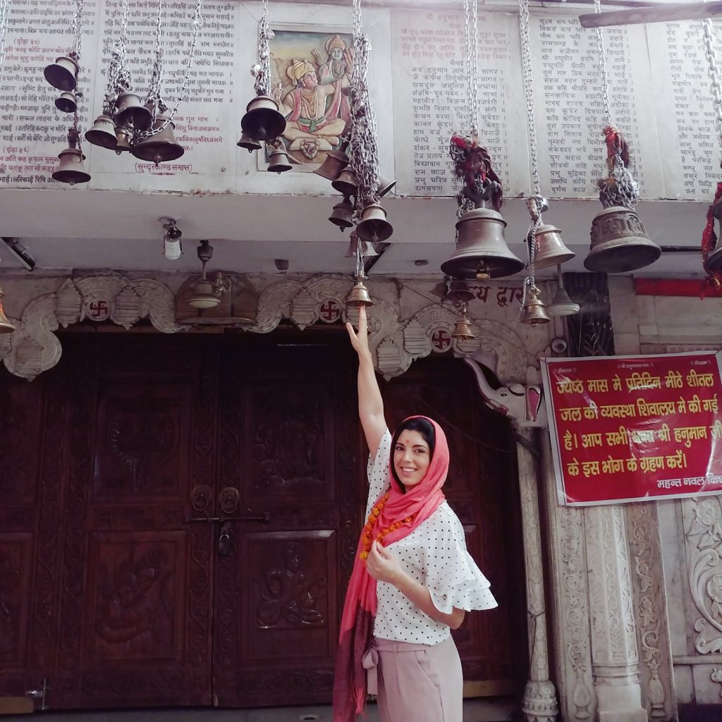 une touriste touche les cloches supendues au plafond du temple 