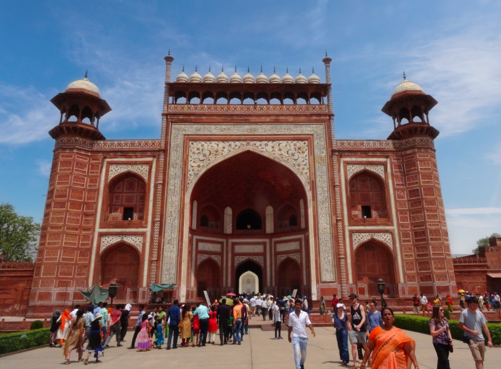la grande porte d'entrée rouge où s'amasse la foule pour découvrir le Taj Mahal
